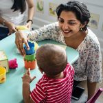 child-building-blocks-with-teacher-nursery